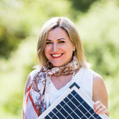 a portrait of Jennifer Lauber Patterson holding a solar panel in her left hand