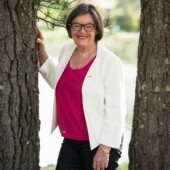 Cathy McGowan standing next to a tree.