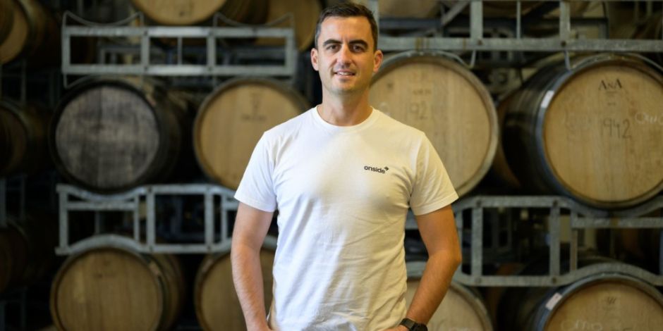 Ryan Higgs from Onside stands in front of wine barrels.